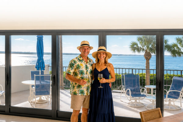 Couple standing in front of hurricane-impact sliding glass doors overlooking Florida waterfront installed by Lemon Bay Glass